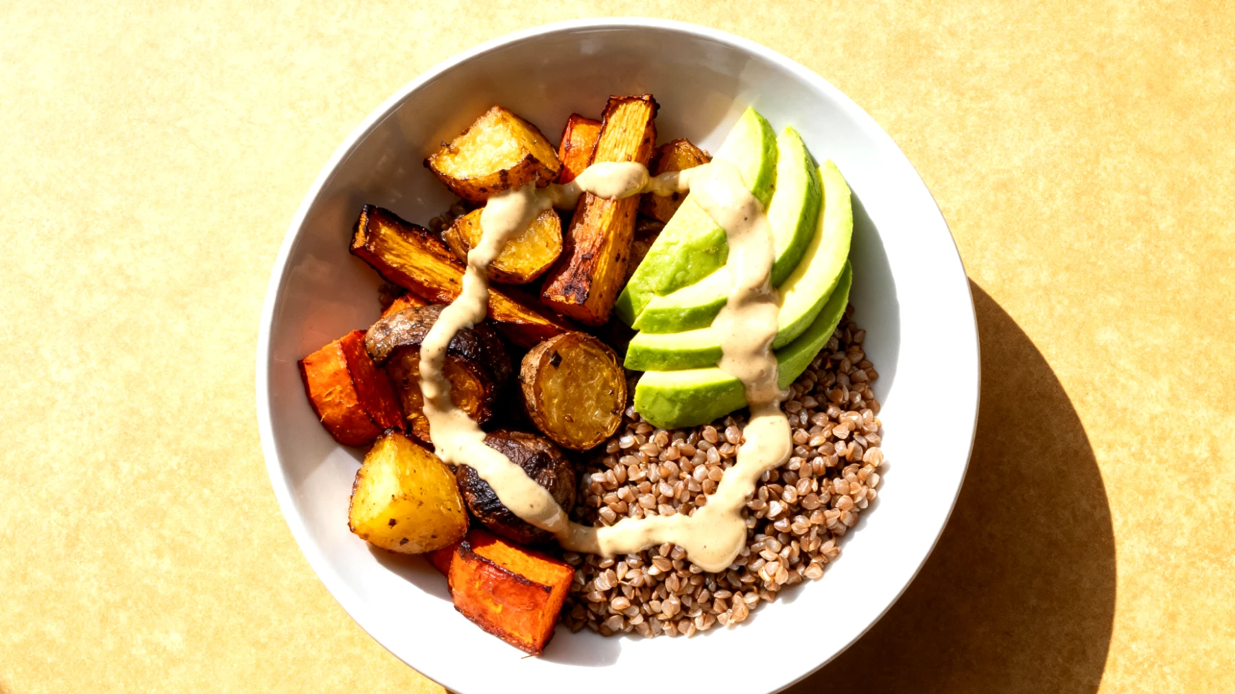 Buchweizen-Bowl mit geröstetem Gemüse, Avocado und Tahini-Dressing"